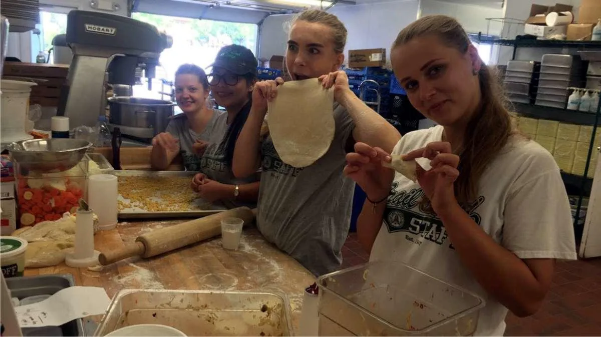 Un grupo de jóvenes trabajando y compartiendo felizmente en el oficio de la cocina en el campamento de verano del programa CC USA de Ventur Camps