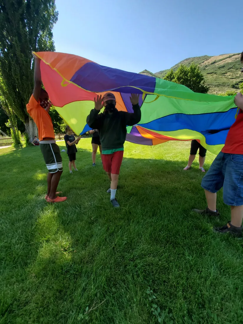 Actividad con niños y un paracaídas de colores en el campamento